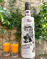 Flasche Sombrero Mexicano Maracuja-Tequila-Likör mit Totenkopf-Design, dekoriert mit Passionsfrüchten, neben zwei Shotgläsern.