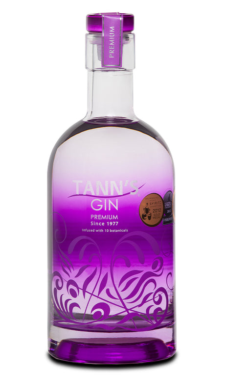 Tann’s Premium Gin in transparenter Flasche mit violettem Design, silberner Verzierung und violettem Verschluss.