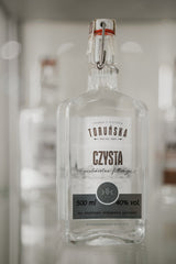 Klare Flasche Toruńska Czysta Wodka 40% vol. mit Bügelverschluss, auf einem Regal oder in einem Display präsentiert.
