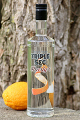 Flasche Triple Sec Charly’s vor Baumrinde, daneben eine ganze Orange.