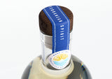 Nahaufnahme des Holzverschlusses einer VITA Vodka Flasche mit blauem Siegelband und mediterranem Design.