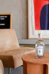 Flasche Ziga Zaga Vodka auf rundem Tisch, im Hintergrund beiger Sessel und modernes Kunstwerk an der Wand.